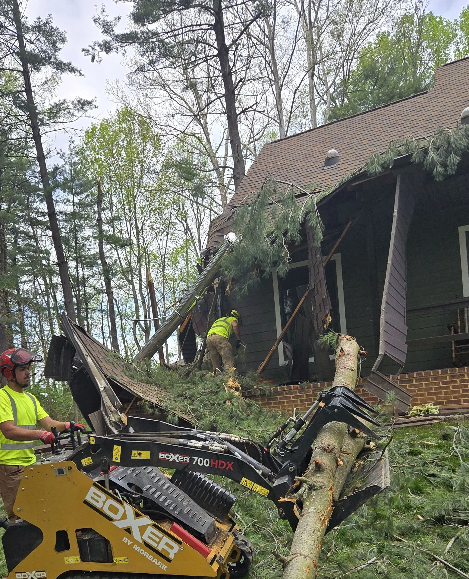 Snyder's Outdoor Solutions crew clearing a tree that fell on a house with a mini-loader.