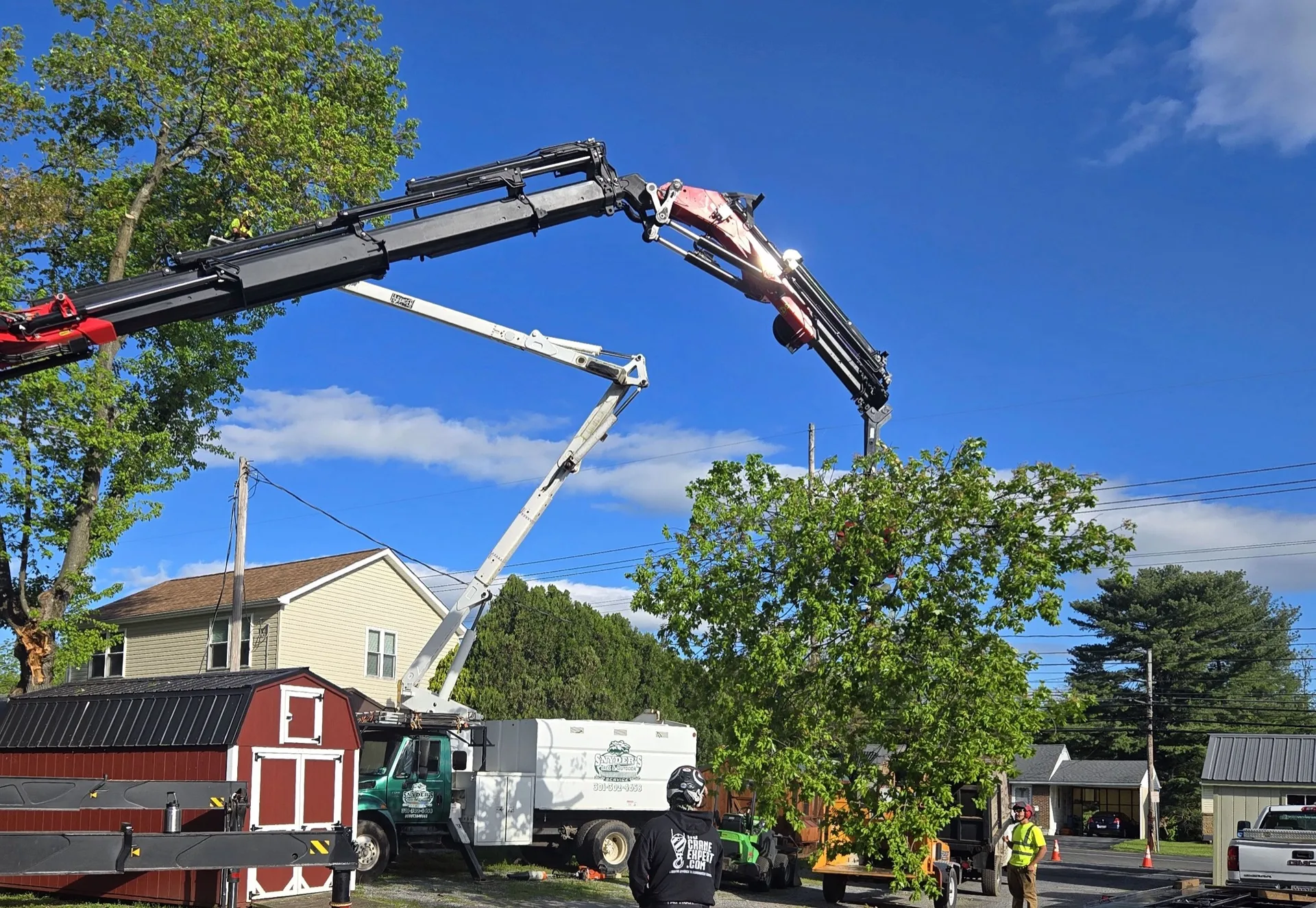 Snyder's Outdoor Solutions crew working a residential tree removal with crane and bucket truck.
