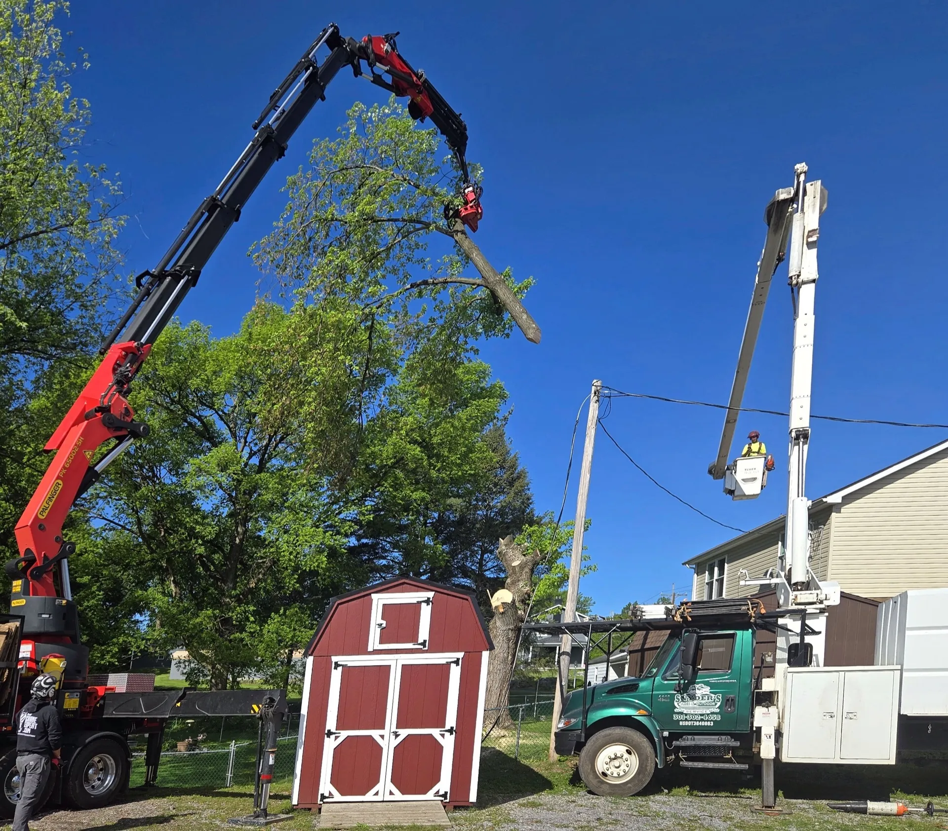 Snyder's full crew with crane, bucket truck, and green pickup on a residential job.